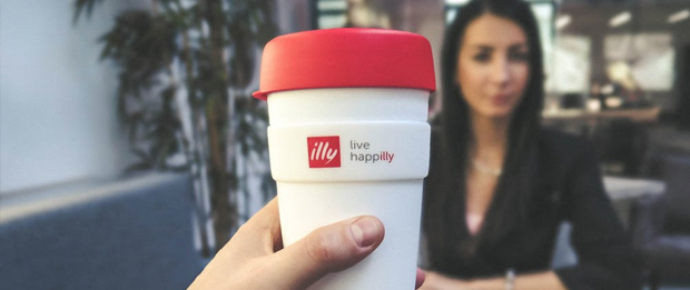 red and white to go mug made by Illy and a businesswoman in the background